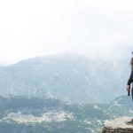 A man standing in a body of water with a mountain in the background