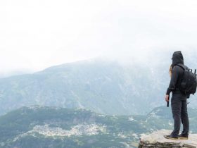 A man standing in a body of water with a mountain in the background