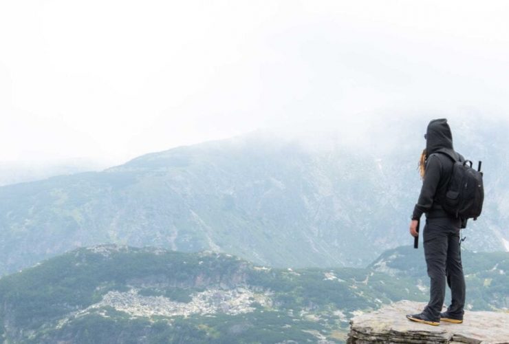 A man standing in a body of water with a mountain in the background