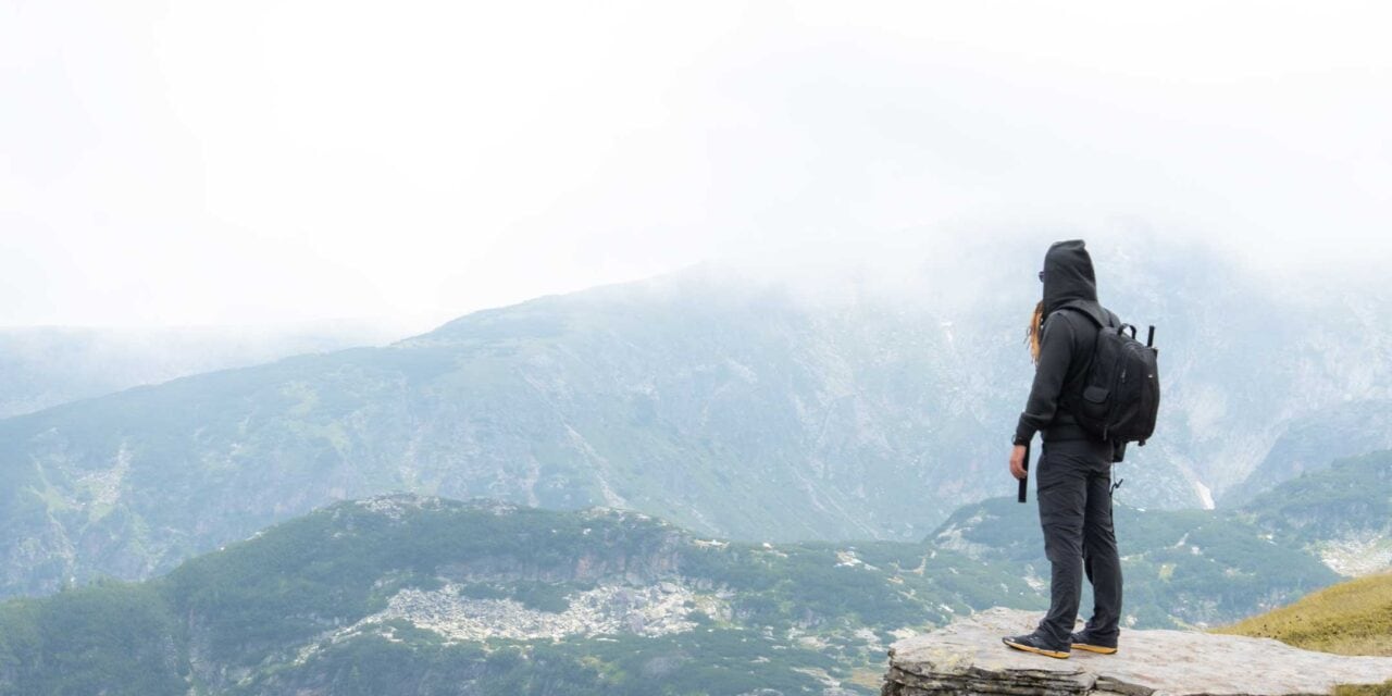 A man standing in a body of water with a mountain in the background